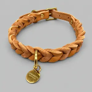Honigfarbenes geflochtenes Lederhalsband Pienza mit goldfarbenen Beschlägen und LEINENREICH-Markenanhänger.